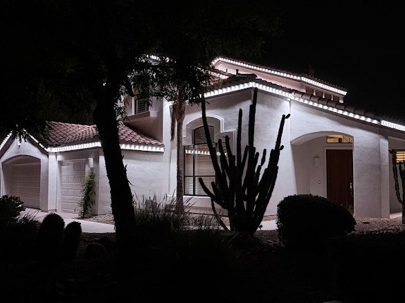 Spanish-style stucco home with bright white permanent LED roofline at night
