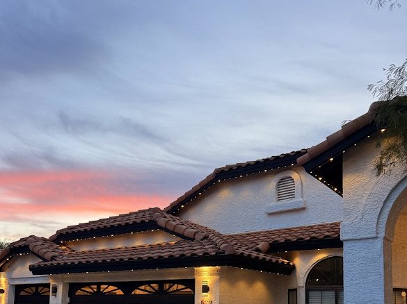 Tile-roof home at sunset with warm permanent LED roofline