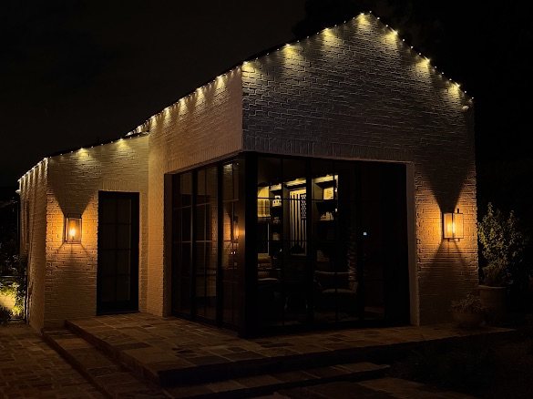 Modern commercial building with warm string lights along the roofline at dusk